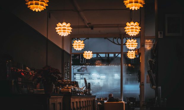 Interior de una cafetería con lámparas cálidas encendidas